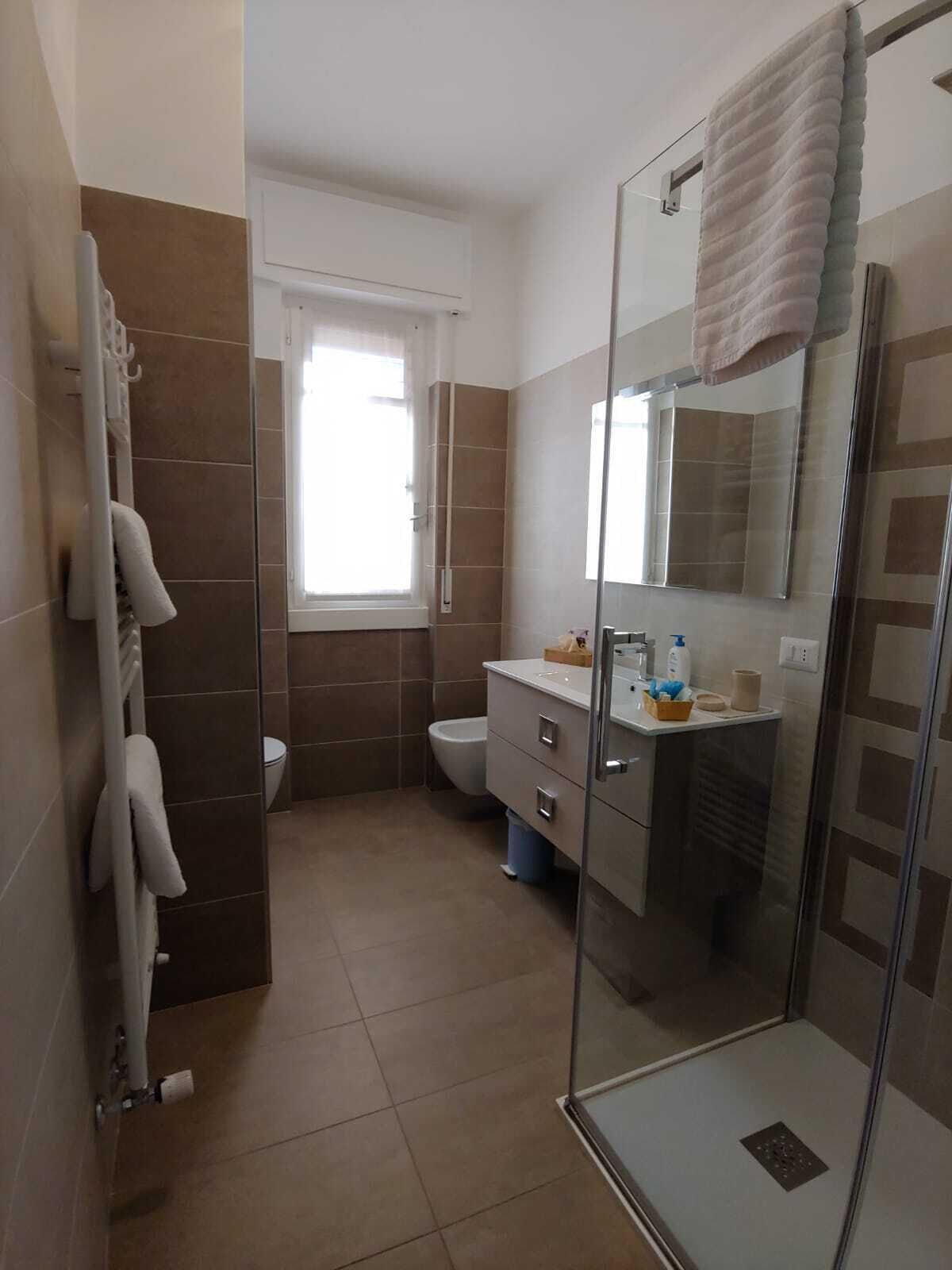 A modern bathroom with a glass shower enclosure, a toilet, and a vanity with a mirror.