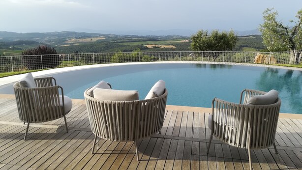 A pool area with wicker chairs and a view of the countryside. - Agriturismo Vicolabate (San Casciano in Val di Pesa)