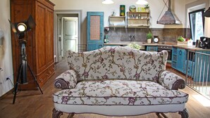A cozy living room with a floral sofa, wooden cabinets, and a vintage camera on a tripod. - Agriturismo Vicolabate (San Casciano in Val di Pesa)