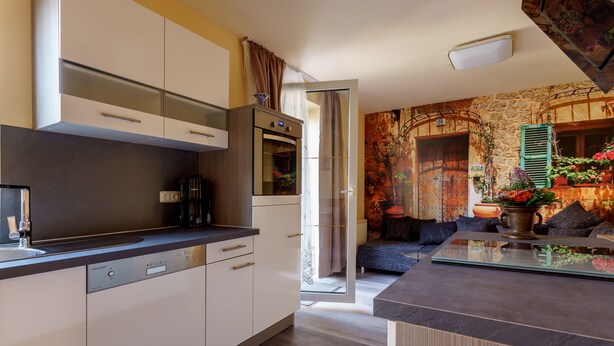 A modern kitchen with built-in appliances, a dishwasher, and a dining area with a glass table and chairs. - Vacation home in Arnstadt for up to 8 people more on request (Arnstadt)