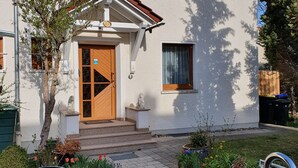 A two-story building with a central entrance, a small porch, and a garden with flowers and shrubs. - Vacation home in Arnstadt for up to 8 people more on request (Arnstadt)