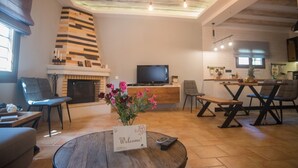Una sala de estar moderna con chimenea, televisor y comedor con sillas y mesa.