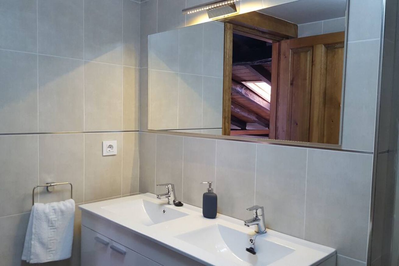 Une salle de bain moderne avec deux lavabos, un miroir et un porte-serviettes.