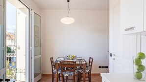 Een eetgedeelte met een tafel voor vier personen, een hanglamp en een uitzicht door een open deur.