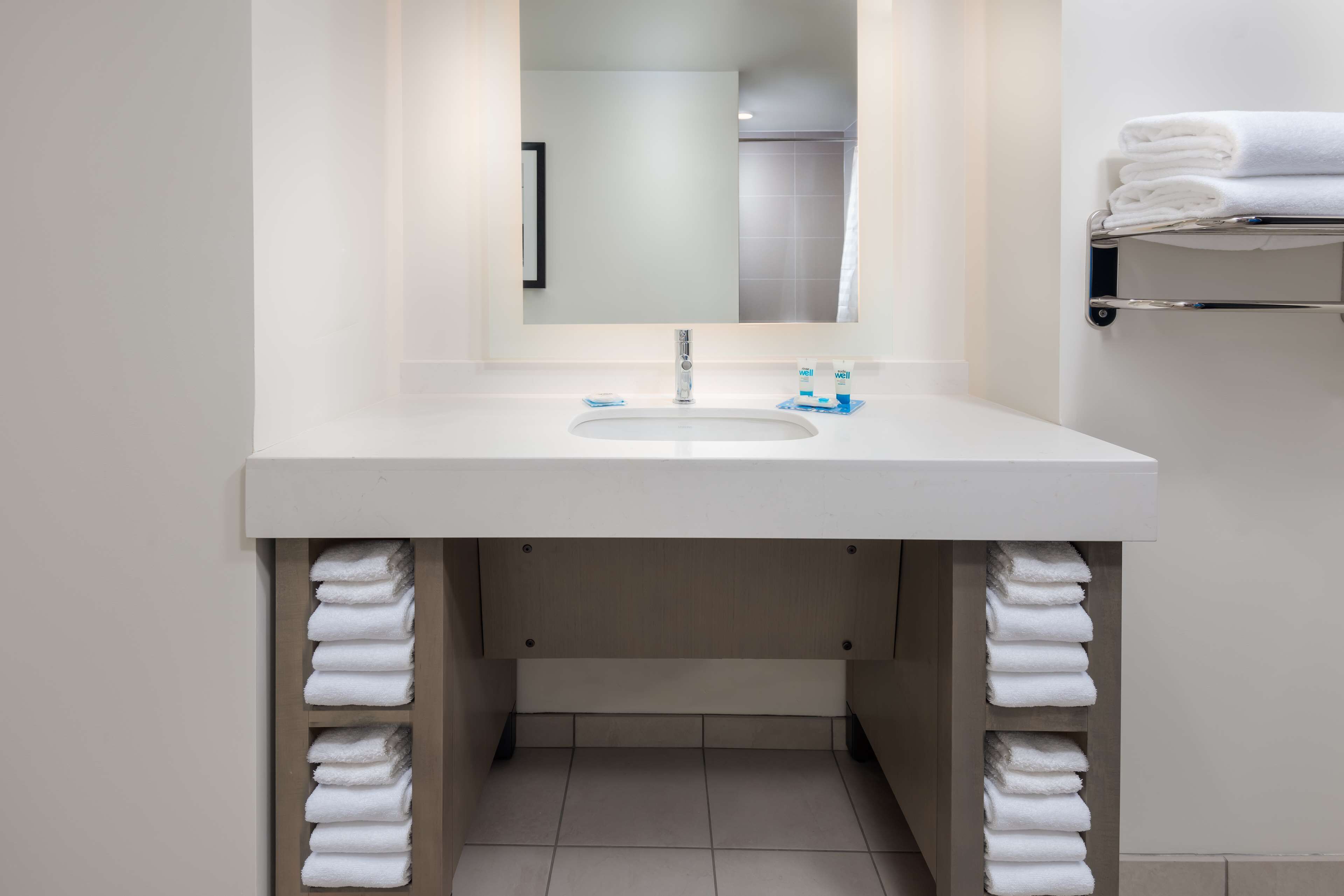 A bathroom with a white sink, mirror, and towel rack.