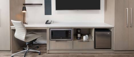 A modern kitchen with a built-in microwave, coffee maker, and refrigerator.