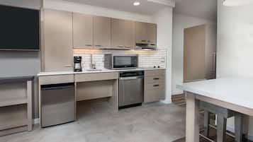 A modern kitchen with built-in appliances, a flat-screen TV, and a dining area.