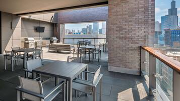 A rooftop patio with outdoor seating, a grill, and a city view.
