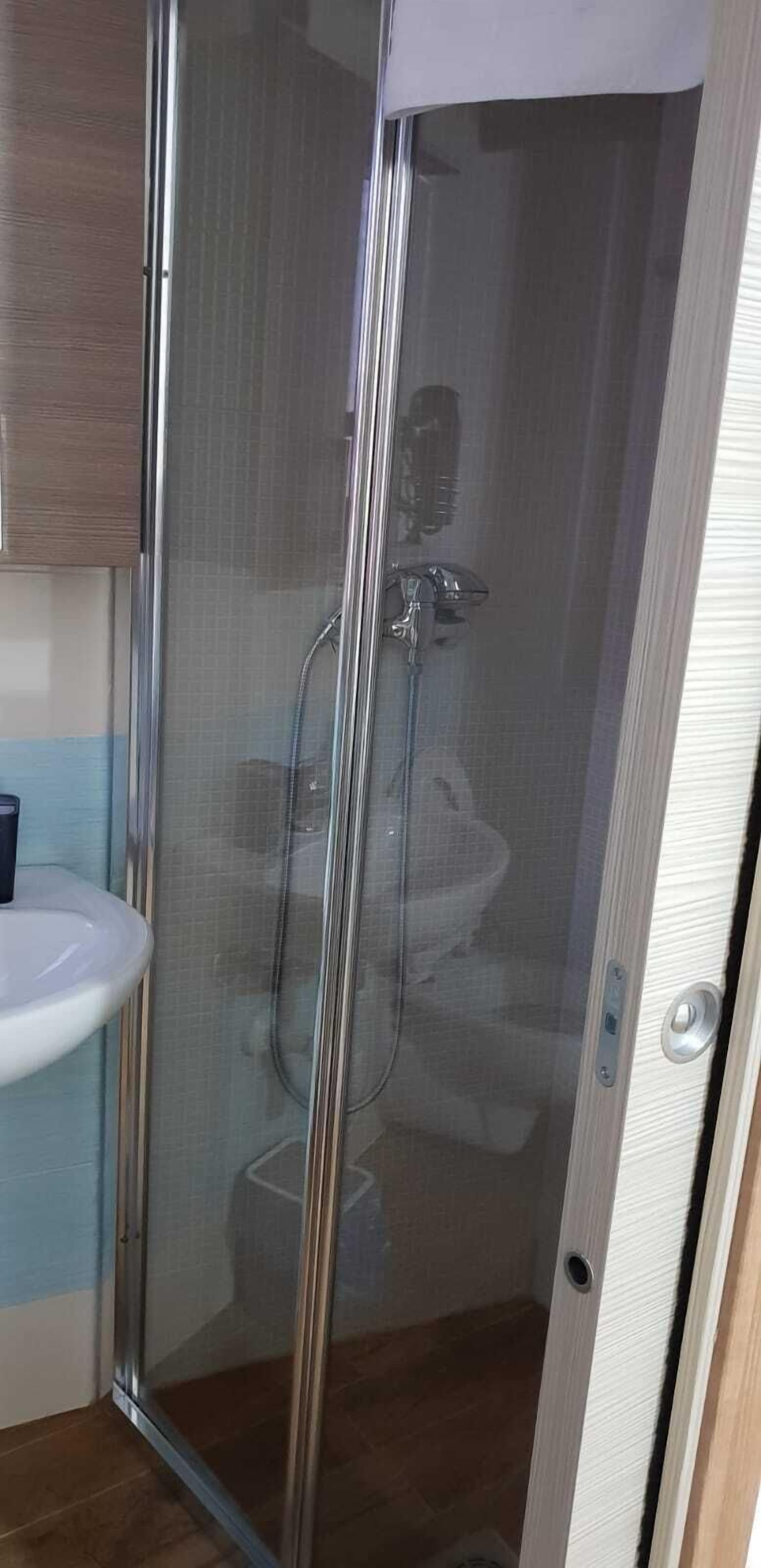 Chuveiro, secador de cabelo, toalhas de banho, papel higiênico