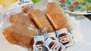 A table with packaged food items including biscuits, bread, and Nutella.