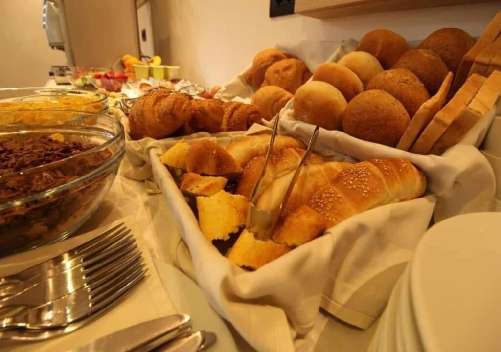 A buffet with various food items including bread rolls, a glass bowl of salad, and utensils.
