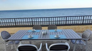 A table and chairs set up on a terrace with a view of the sea.