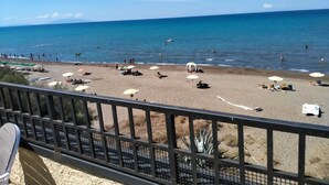 A beach with umbrellas and sun loungers, a railing, and a clear view of the ocean.