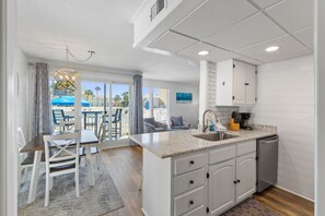 A modern kitchen with white cabinetry, a granite countertop, and a built-in dishwasher.