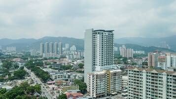 A high-rise building with a modern design, surrounded by other residential buildings and a road with vehicles.