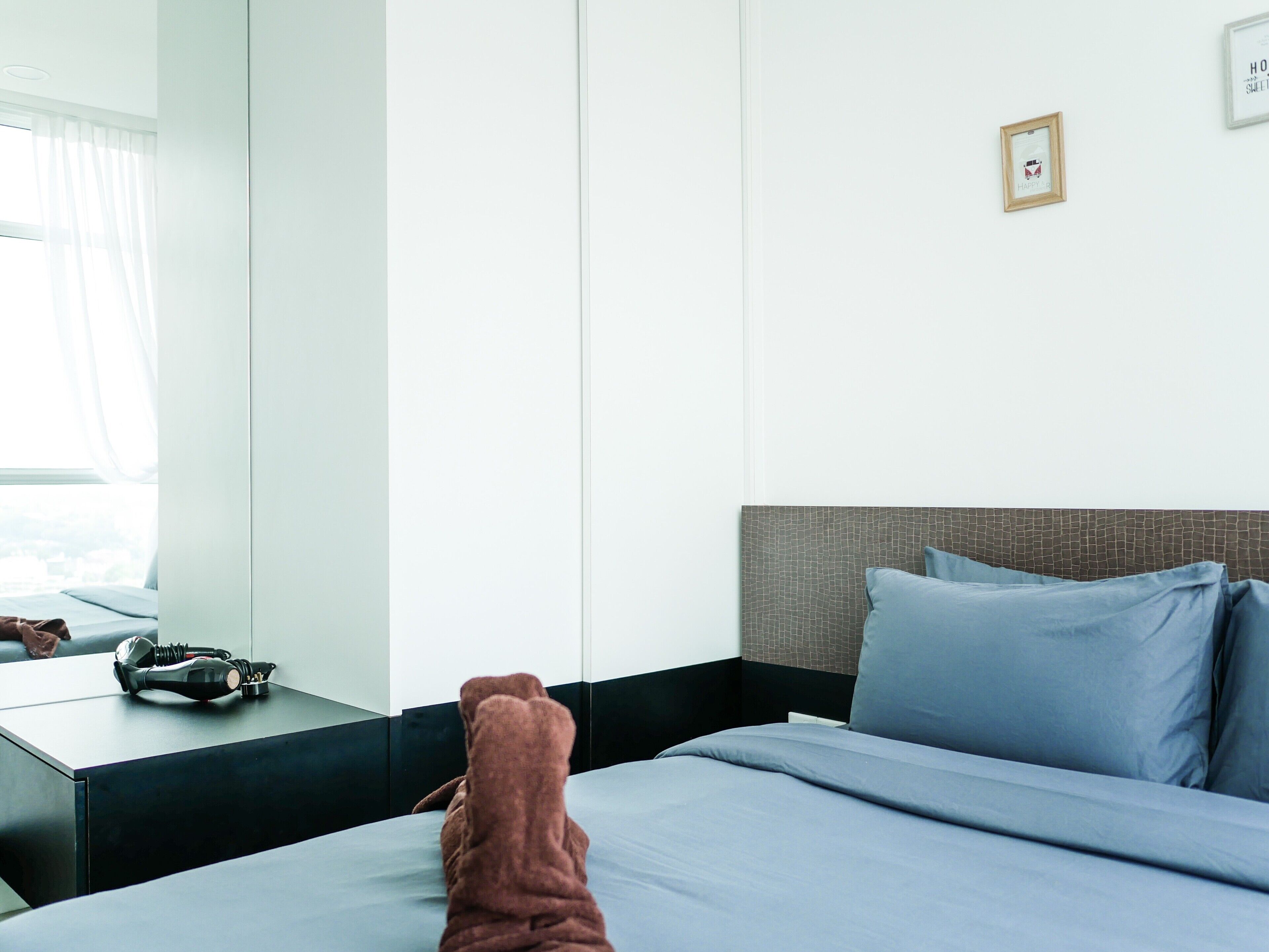 Een hotelkamer met een bed, nachtkastje en een raam met gordijnen.