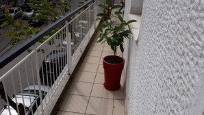 Een balkon met een bloempot, betegelde vloer en een hekwerk.
