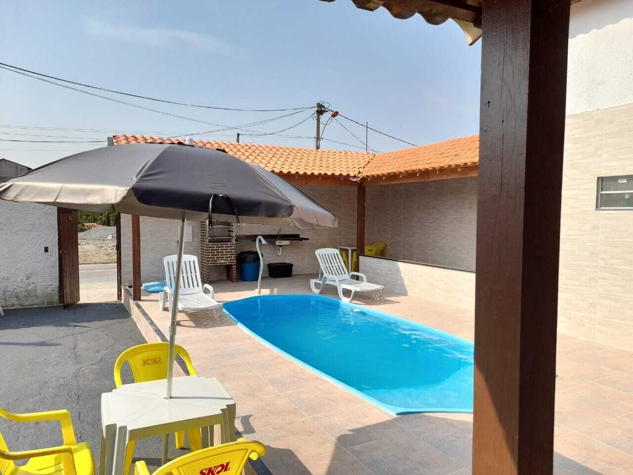 Una piscina con sillas de descanso y una mesa, rodeada por un porche cubierto.