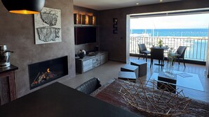 A modern living room with a fireplace, a flat-screen TV, and a balcony with a view of the sea. - Upscale apartment in a quiet location, accessible for disabled people (Hyères)