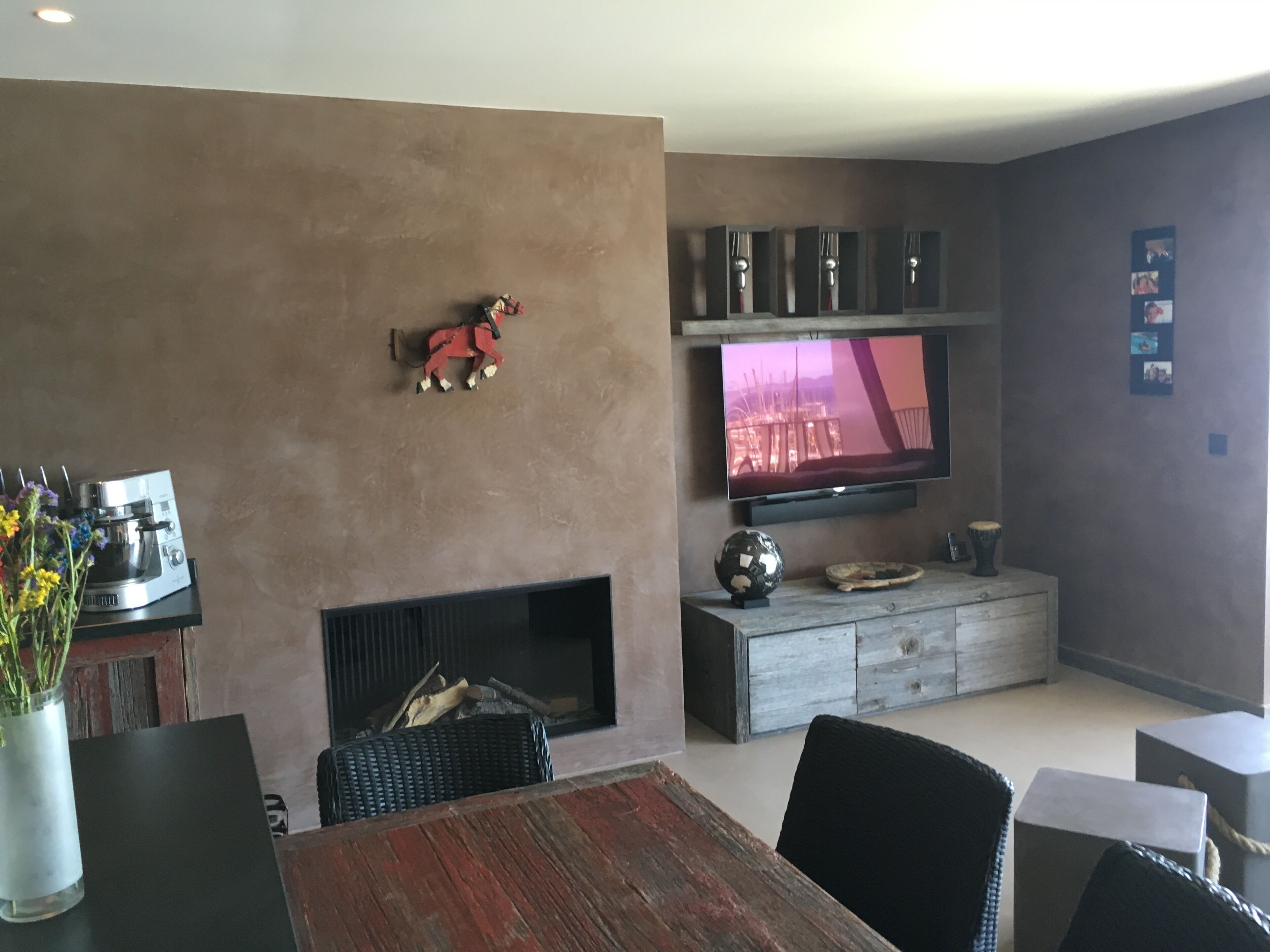 A modern living room with a fireplace, a flat-screen TV mounted on the wall, and a coffee machine on a side table.