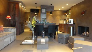 A modern living room with a sofa, coffee table, and decorative vase. There is a dining area with chairs and a kitchen with a coffee machine. - Upscale apartment in a quiet location, accessible for disabled people (Hyères)