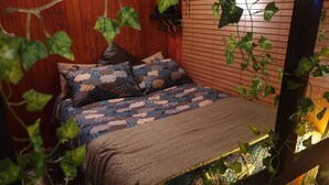 Un lit avec une literie à motifs, une tête de lit en bois et un luminaire fixé au mur.