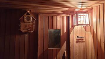 A wooden interior with a clock, a framed picture, and a door with a sign.