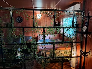 Una habitación con cama, un reloj y una ventana con persianas.