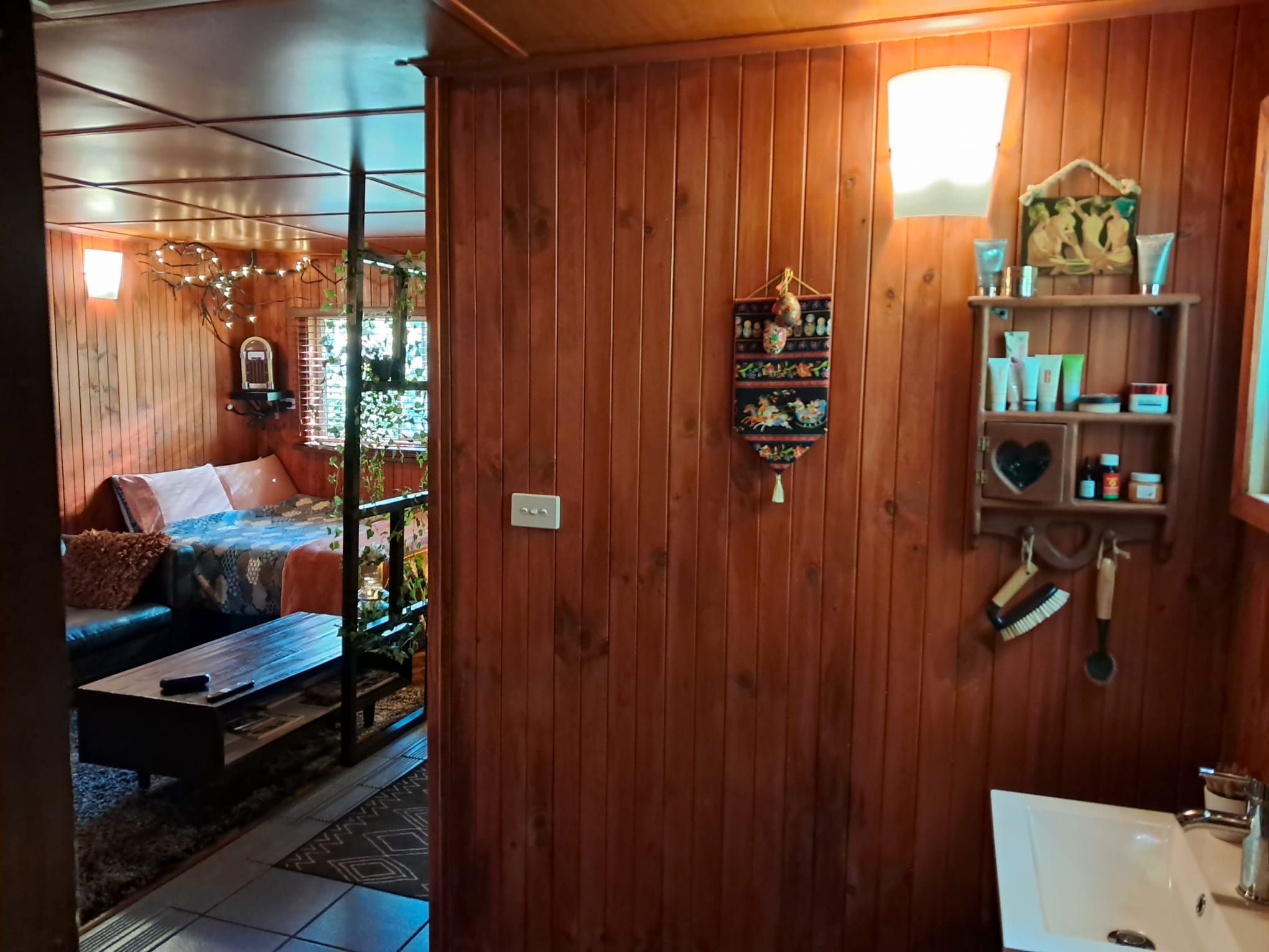A wooden interior with a sofa, a hanging decorative item, and a shelf with toiletries.