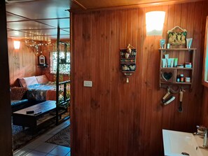 Un intérieur en bois avec un canapé, un objet décoratif suspendu et une étagère contenant des articles de toilette.