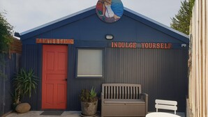 Un bâtiment avec une porte rouge, un banc et une table à l’extérieur.