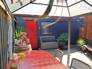 Un espacio de estar al aire libre cubierto con una mesa roja, sillas y plantas en macetas.