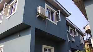 A multi-story building with external air conditioning units, a central entrance, and a visible balcony. - KINGS PALACE HOTEL & LOUNGE (Ipaja)