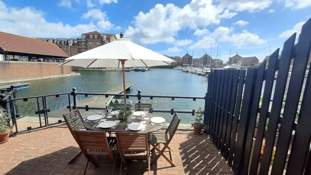 A terrace with a table set for two, overlooking a canal with boats and buildings in the background. - Three floor townhouse next to the water for families and friends with 3 bedrooms (Eastbourne)