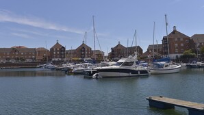 A marina with several boats docked, surrounded by multi-story buildings with red-tiled roofs. - Three floor townhouse next to the water for families and friends with 3 bedrooms (Eastbourne)
