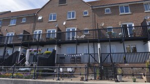 A row of terraced houses with balconies, a gated entrance, and outdoor seating. - Three floor townhouse next to the water for families and friends with 3 bedrooms (Eastbourne)