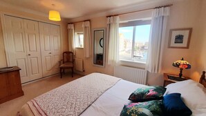 A bedroom with a bed, a chair, a window with a view, a lamp, and a door. - Three floor townhouse next to the water for families and friends with 3 bedrooms (Eastbourne)