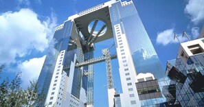 A modern skyscraper with a distinctive circular feature at the top, surrounded by other high-rise buildings.