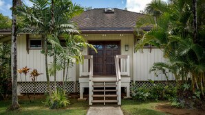 A house with a front porch, a door, and a small window. - Quaint stand-alone cottage - 2 bedroom 2 bath (Princeville)