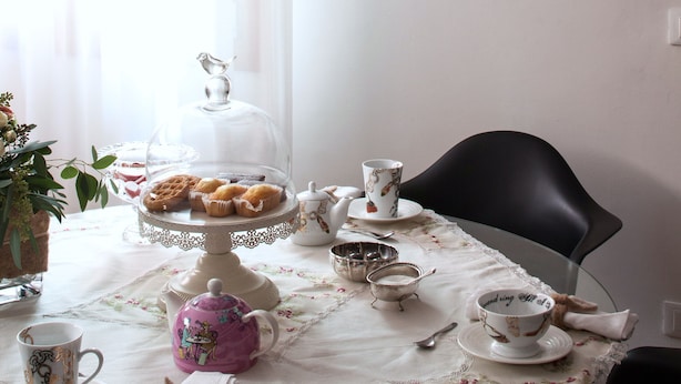 A dining area with a table set for tea, a teapot, cups, and a cake stand. - Laguna Boutique Apartments | 2-bedroom with patio & parking in Venice Mestre (Venezia)