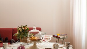 A dining area with a table set for a meal, a red sofa, and a window with curtains. - Laguna Boutique Apartments | 2-bedroom with patio & parking in Venice Mestre (Venezia)