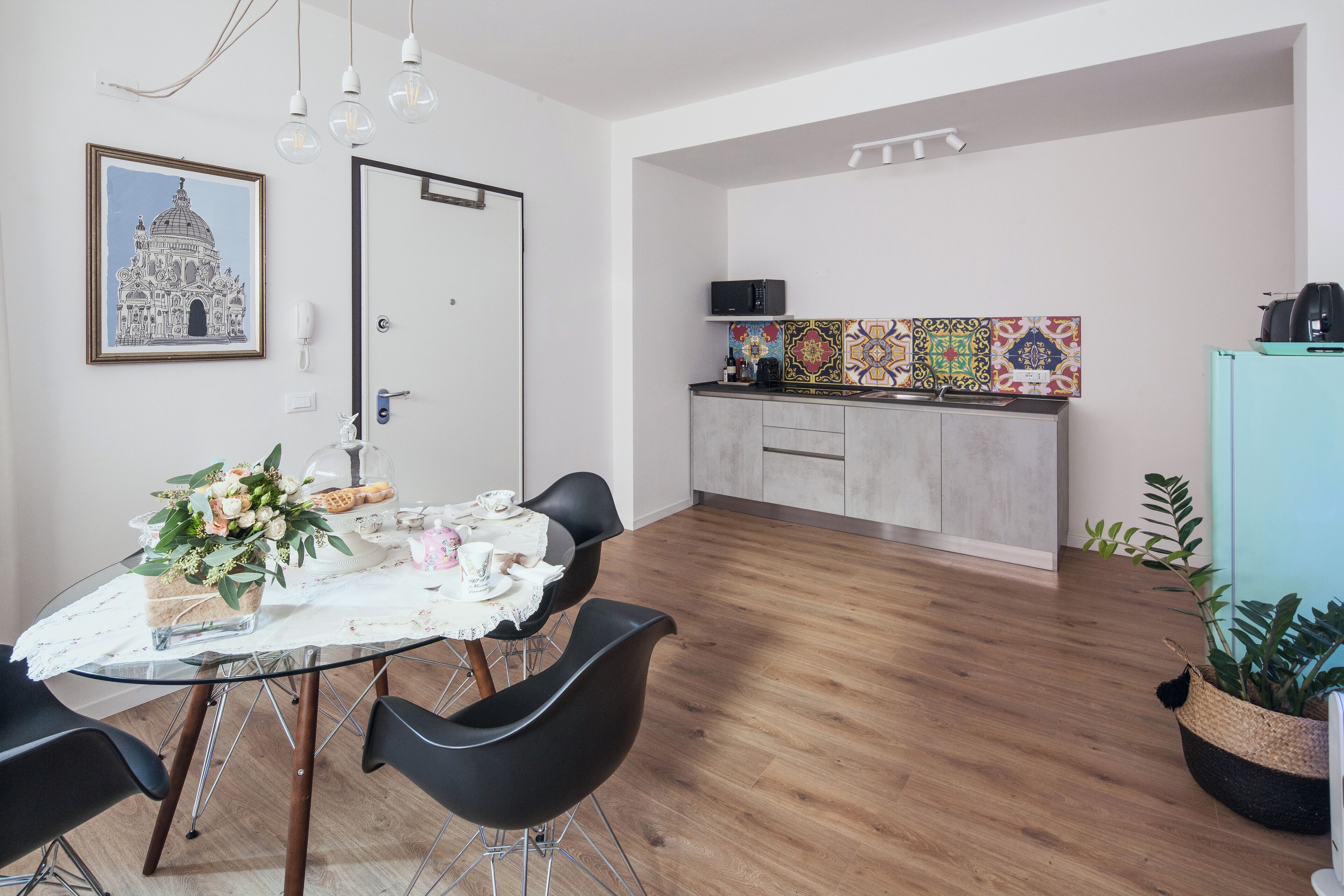 A modern kitchen with a microwave, toaster, and colorful backsplash.