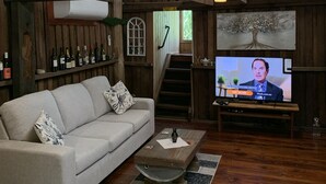 Ein rustikales Wohnzimmer mit einer Couch, einem Couchtisch und einem Fernseher, der eine Nachrichtensendung zeigt.