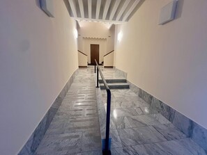 Una moderna scala con pavimento in marmo e corrimano in metallo, che conduce a una porta in legno in cima.