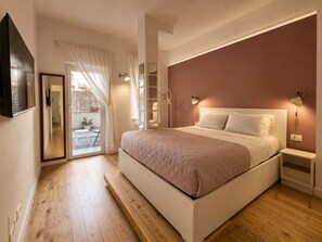 A bedroom with a large bed, a bedside table, a nightstand, a wall-mounted lamp, and a mirror.
