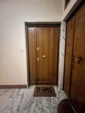 Una porta in legno con un zerbino che riporta la scritta 'HOME' su un pavimento in marmo.