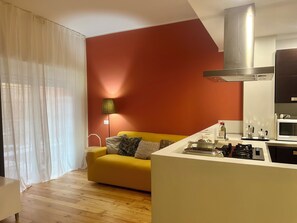 Ein moderner Wohnraum mit einem gelben Sofa, einer Küchenzeile mit Herd und einer roten Akzentwand.