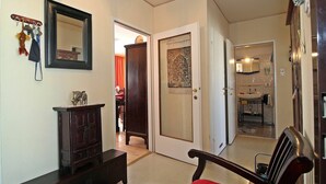 A hallway with a wooden cabinet, a red chair, a coat rack with keys, and a door leading to a bathroom. - Beautiful apartment for 4 guests with WIFI, TV and terrace (Vienna)