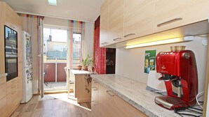 A modern kitchen with wooden cabinets, a red coffee machine, and a view of the outside balcony. - Beautiful apartment for 4 guests with WIFI, TV and terrace (Vienna)