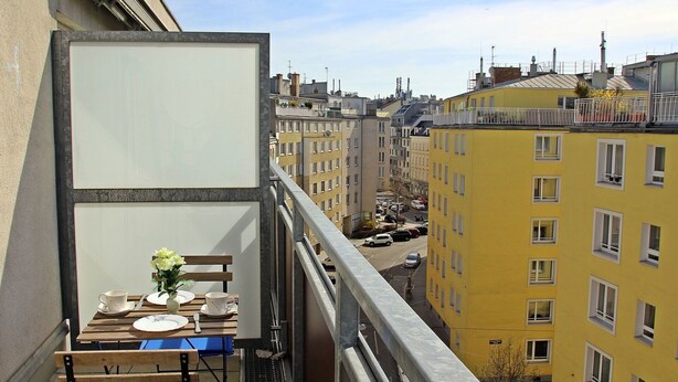 A balcony with a table set for two, overlooking a cityscape with yellow buildings. - Beautiful apartment for 4 guests with WIFI, TV and terrace (Vienna)